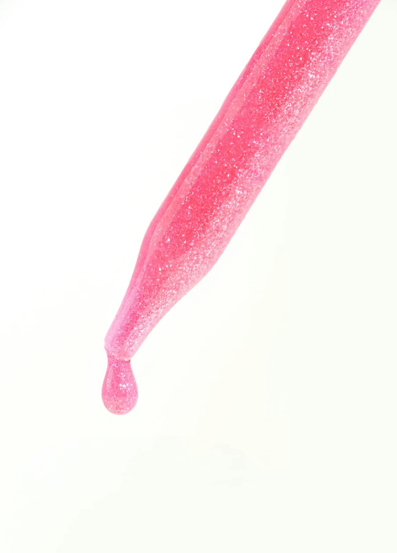 Pink facial serum dripping from a glass dropper